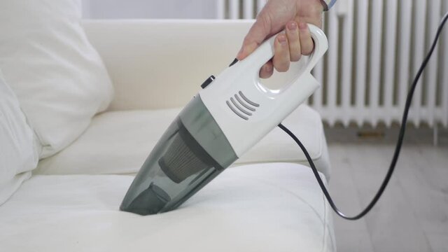 Man Using a Vacuum Cleaner in Household Activities to Clean the Sofa Surface from Dust.