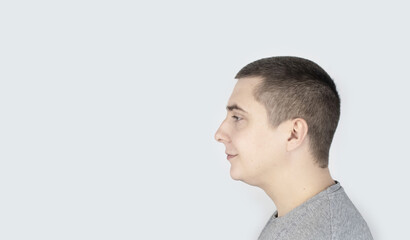 Fototapeta premium The man shows his double chin on a gray background. Obesity, face roundness and excess weight. Place for your text.