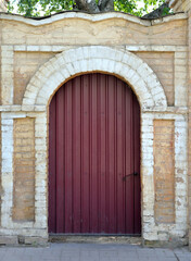 Fototapeta na wymiar Metal door in old stone fence of house