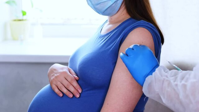 Pregnant Vaccination. Doctor giving COVID -19 coronavirus vaccine injection to pregnant woman. Doctor Wearing Blue Gloves Vaccinating Young Pregnant Woman In Clinic. People vaccination concept. Slow