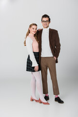 full length view of young couple in retro outfit posing on grey background