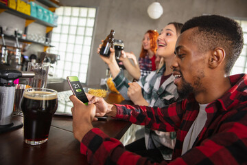 Group of friends watching sport match together. Emotional fans cheering for favourite team, watching on exciting game. Concept of friendship, leisure activity, emotions