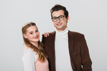 smiling woman leaning on shoulder of man in velvet blazer isolated on grey