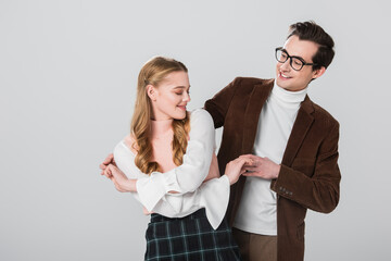 old fashioned man in eyeglasses dancing with young girlfriend isolated on grey
