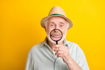 Photo of funky sweet age gentleman wear green shirt spectacles headwear loupe cover mouth smiling isolated yellow color background