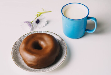 Donut de chocolate fresco delicioso sobre fondo blanco. Apetitosa y sabrosa rosquilla glaseada lista para comer con una taza de leche fresca
