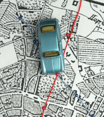 City map, blue toy car, top view. Two routes are marked with pins: red and blue. Concept: route selection, pathfinding, navigation, goals.