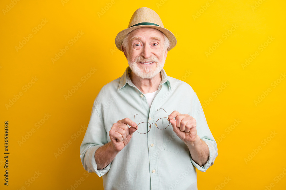 Poster Photo of charming pretty mature man dressed green shirt cap arm glasses smiling isolated yellow color background