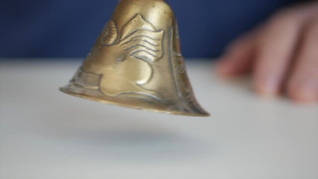 Closeup Hand Ringing with a Bronze Handbell Demanding Attention and Silence. 