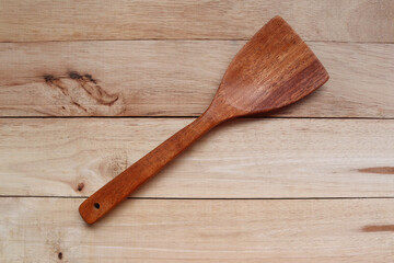 Wooden spoon for kitchen appliances isolated on wooden background closeup.