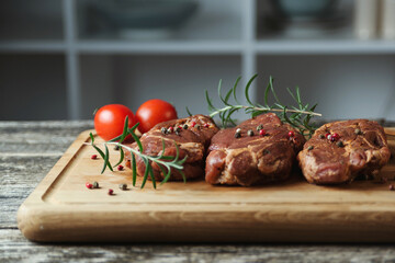 Fresh steaks on wooden board at kitchen table. Skirt steak on woods chopping board with herbs and tomatoes.
