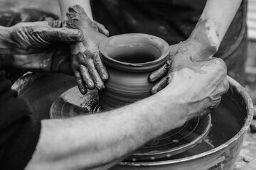 Potters and child hands. Family working on pottery wheel. Dad and child making ceramic pot together.