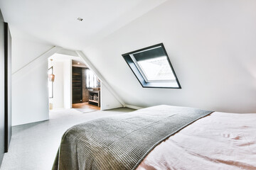 Interior of contemporary bedroom with white walls and open bathroom in attic of house