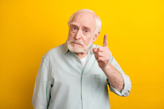 Photo of irritated annoyed mature man dressed green shirt rising finger saying no isolated yellow color background
