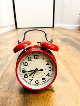 Red alarm clock on wooden floor. Time concept. 