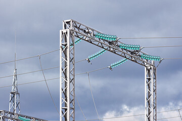 High voltage electric glass insulator of electric high voltage electric transmission power tower and lightning protection mast over cloudy stormy dark sky.