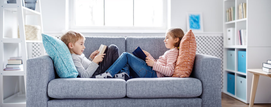 Cute children sitting on the soft sofa and reading books