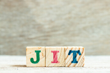 Alphabet letter block in word JIT (abbreviation of just in time) on wood background