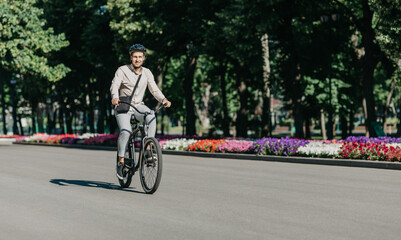 Cheerful young employee with helmet on utility bicycle rides to modern workplace