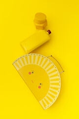 Yellow case, bottle and container construction hovering on a yellow background. Creative top view, floating.