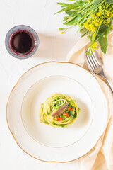 Typical italina dish: spaghetti with broccoli, anchovies and red pepper. White background and fresh broccoli flowers on back.