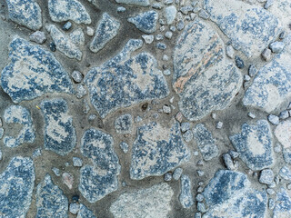 Piece of road paved with old cobblestones, abstract background, top view.