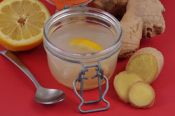 Infusion de gingembre et de citron frais dans un bocal en verre en gros plan sur fond rouge