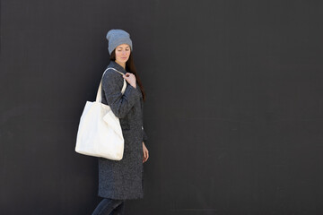 Woman holding white textile tote eco bag in urban area. Ecology or environment protection concept. White eco bag for mock up.