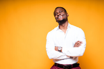 Happy egyptian man in white shirt smiles broadly with his arms crossed on his chest and looking at the camera