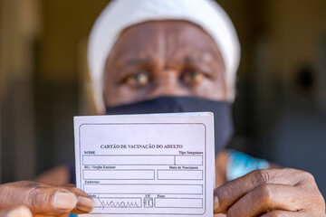 Mulher idosa mostra cartão de vacinação contra Covid 19, em zona rural de Guarani, Minas Gerais