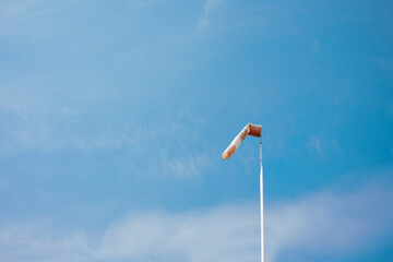 red white striped wind sock in front of blue sky