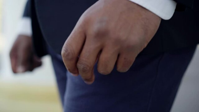 Close-up of African American male hand snapping fingers. Unrecognizable young man in suit standing outdoors. Anxiety and lifestyle