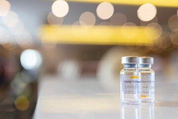 Close up photo of corona vaccine vial with blur background and beautiful bouquet. Drug prepare for immunization againt covid 19 pandemic.Selective focus at medicine vial.Medical concept.