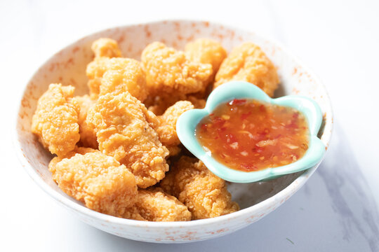 Fried chicken with chicken dipping sauce in a ceramic cup on a white table.