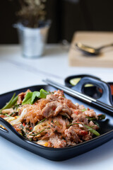 Dried sukiyaki and pork in a black plate with sukiyaki sauce