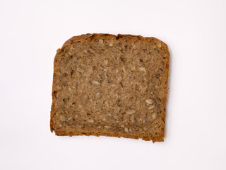 Slice of wholegrain bread with seeds of sunflower, flax, and sesame. Healthy vegetarian food. Isolated flatlay.