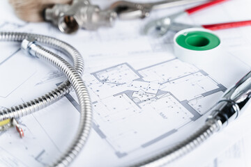 Plumbing project in house.Drawing,diagrams,plan of water supply of apartment,building.Man repairer making repairs at home.Devices,accessories, hose,tap,adjustable wrench,pressure reducer,tape measure