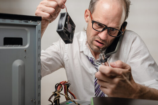 Confused Man Holding Computer Fan And Talking With Technical Support