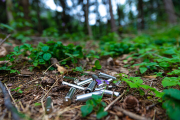 Exhausted batteries thrown in the grass, in a wood. Ecology and environmental protection. Disposal of polluting waste.