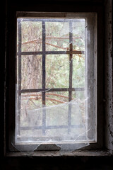 Dirty old window with broken glass and bars in abandoned house in ghost town Pripyat, Chernobyl Exclusion Zone, Ukraine. Vertical photo