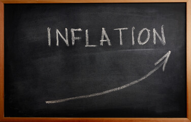 inflation is growing a lot. symbol of an up arrow and the word inflation written in chalk on a blackboard