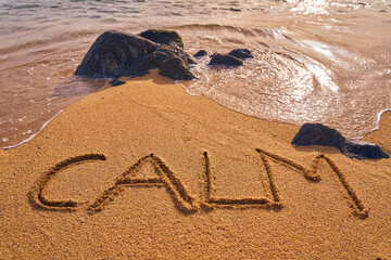 calm written on the beach next to the water and some rocks
