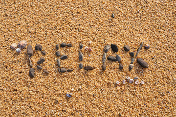 the word relax written with black stones on the beach sand