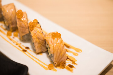 Aburi salmon roll shushi in white Japanese plate.