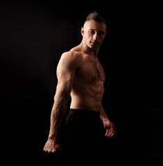 Fototapeta na wymiar Powerful strong sport man with muscular bodybuilder looking sexy on black dark background. Closeup