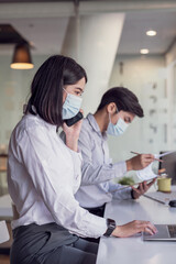 Asian businessman and businesswoman wear a mask to work at the office.