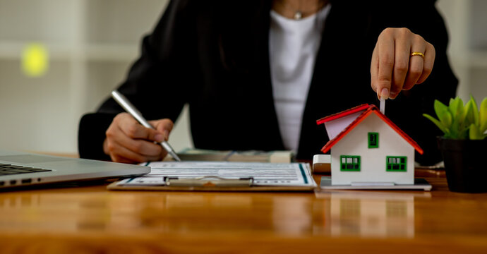 Female woman hands holding home model, small miniature white toy house. agencies,Mortgage,loan,agreement,property insurance dream moving home and real estate concept,