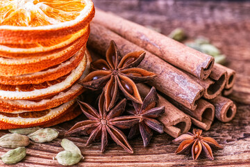 Dry orange slices, anise stars, cinnamon, cardamom and roasted coffee beans on a wooden table. 