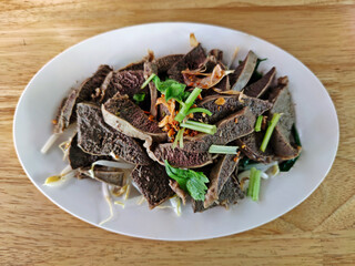Delicious scalded beef spleen served in white plate on wooden table.