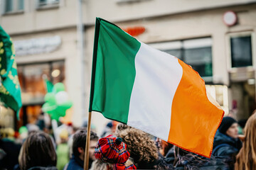 National Flag of Ireland close-up in hands of girl in national beret hat in city street,...